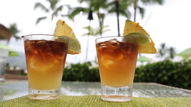 Alcoholic drinks for romantic couple standing on table on vacation resort. Close up of two Mai Tai drinks on Hawaii. Typical Hawaiian drink.