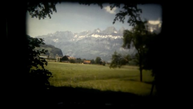 A peaceful view of snowy mountains from a warm spot surrounded by branches. Vintage shot.
