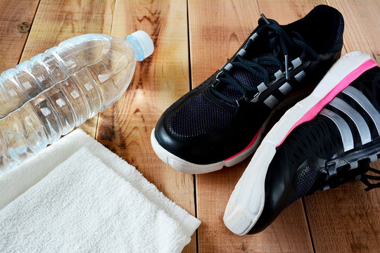 Sport shoes and towel, bottle of water on wooden.