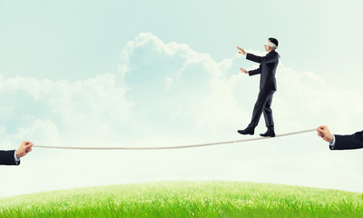 Business concept of risk support and assistance with man balancing on rope