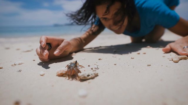 The island of Bali. Beach. Arthropods. Brunette on the beach. She saw chlenistonogovo and decided to play with him. The woman touched chlenistonogovo and received a lot of positive emotions.