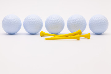 White golf balls and wooden tees on the white background.