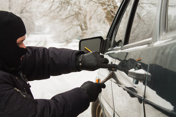 Thief breaks into a car lock. criminal steals auto