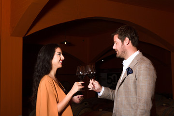 Smiling stylish young couple holding wineglasses in the winery c