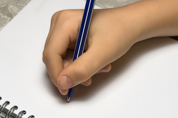 child's hand writing on a white sheet of notebook