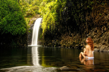 Young woman sitting at Wainibau Waterfall on Taveuni Island, Fij