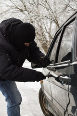 criminal in a mask hijacks auto. Opening the car lock. Vertical photo