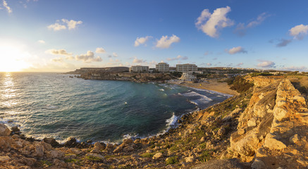 Fototapeta na wymiar Ghajn Tuffieha, Malta - Panoramic skyline view of Golden Bay, Malta's most beautiful sandy beach at sunset with blue sky and clouds