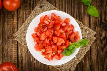 Tomatoes (diced) on wooden background (selective focus)