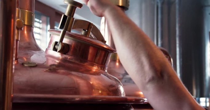 Craft brewery equipment 4k close-up video. Beer production technique: man hand close steel vats tank. Microbrewery and brew pub concept.