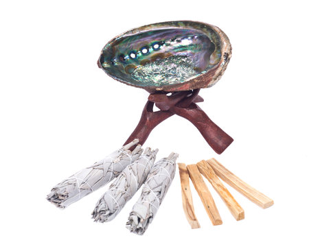 Sage smudge stick, bright polished rainbow abalone shell with wooden cobra stand and palo  santo smudging sticks isolated on white background