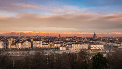 Fototapeta na wymiar Torino (Turin, Italy): expansive cityscape at dusk with scenic colorful light on the snowcapped Alps in the background.