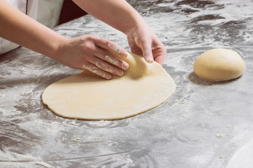 Woman working with dough in bakery, on a table from steel. Working process