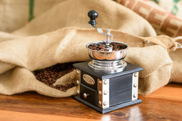Antike Kaffeemühle mit Sack und Bohnen