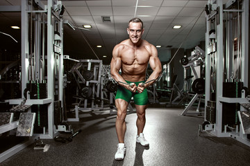 Fototapeta na wymiar Muscular bodybuilder guy doing exercises workout in gym