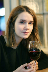 Closeup portrait of a pretty girl with a glass/Portrait of elegant charming young glamour woman in restaurant with glass of red wine