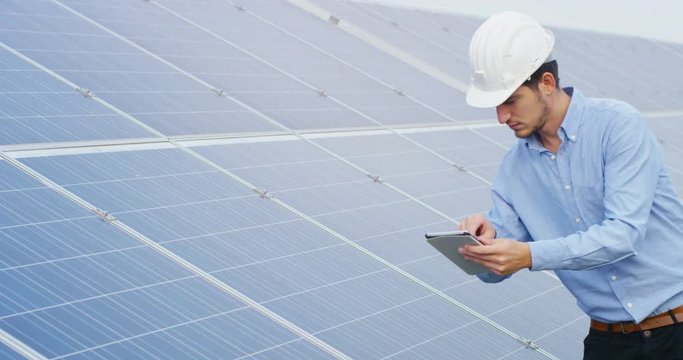 In a field photovoltaic solar panels an engineer, thanks to holography and augmented reality, check their operation with the sun and their productivity. Concept:renewable energy,technology,electricity