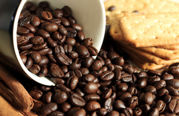 Roasted coffee beans in black mug on a wooden table with warm fall colors, soft-focus in the background. over light
