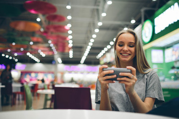 Girl texting on the smart phone in a restaurant terrace with an unfocused background