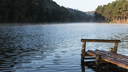 The wooden port at the reservoir with mist in the morning.