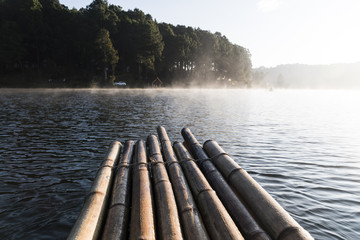 The bamboo raft floating on the reservoir with mist in the morni
