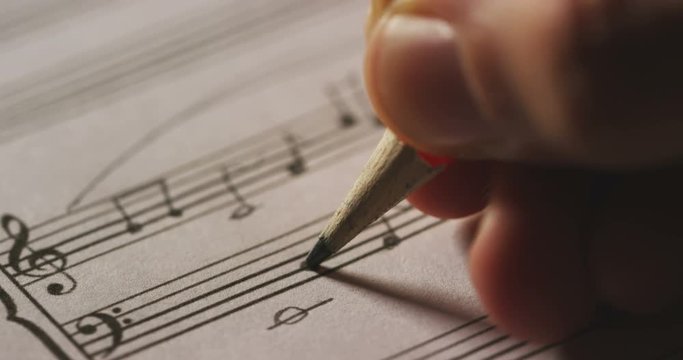 A musician or composer composes a song or a musical work, writing notes in pencil on the pentagram. The composer, first hears the sound of the note then writes and so on is composed the music. Concept