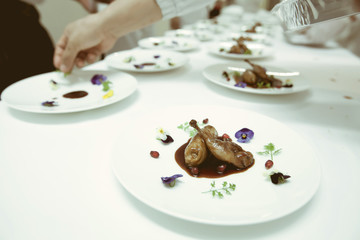 chef using chopsticks tong sliced beef put on the white plate in