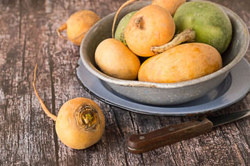  Turnip.   Turnip in an old metal bowl and a knife on a wooden table.