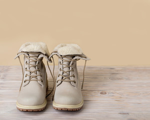 Bright leather winter boots on a light wooden background.
