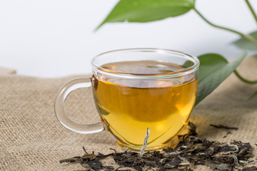 Cup with tea and green leaf on the white background