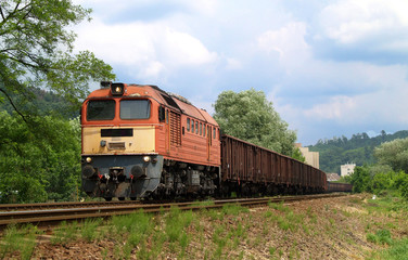Fototapeta premium Długi pociąg towarowy ciągnięty przez potężną lokomotywę spalinową