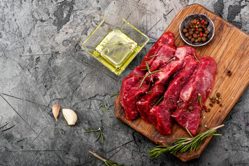 Raw meat with olive oil, spices and rosemary on wooden board. Fresh beef. Ready to roasting. Top view.