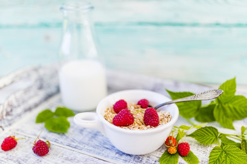 Muesli and yogurt with fresh raspberry fruit on wooden tray.
