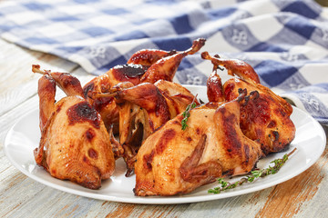 barbeque quails with thyme on dish on white table