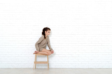 Young and beautiful woman sits on the wooden chair. She is weari