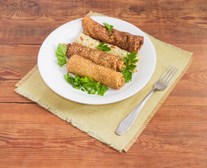 Pancakes filled with meat stuffing on white dish and fork