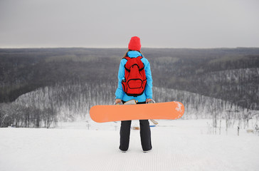 The girl with a snowboard standing on her back on top of a monochrome background of a winter landscape