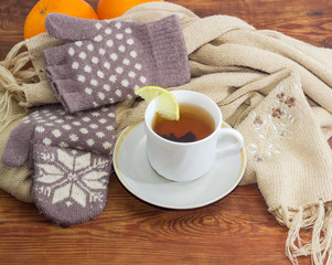 Cup of tea on background of woolen mittens and scarf