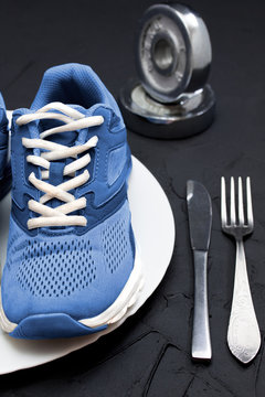Sport shoes on wtite plate, fork and knife.