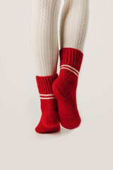 Female legs in white stockings and red knit socks.