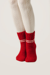 Obraz na płótnie Canvas Female legs in white stockings and red knit socks.