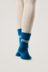 Female legs in white stockings and blue knitted socks.