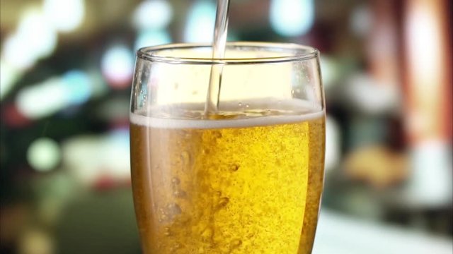 Beer is pouring from the top into the glass. Slow motion 120 fps.