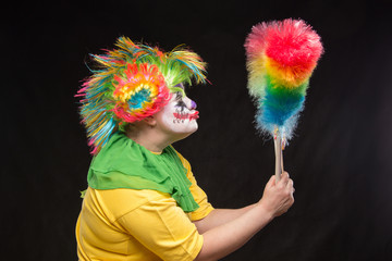 Scary clown with mohawk and a smile with a lollipop on a black b