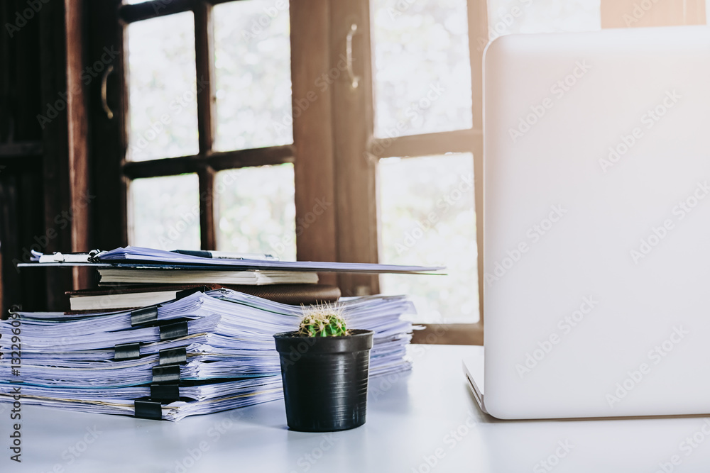 Poster stack of business report paper file on modern white office desk with laptop computer.close up busine