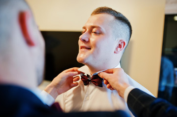 Best man helping wear groom on his wedding day.