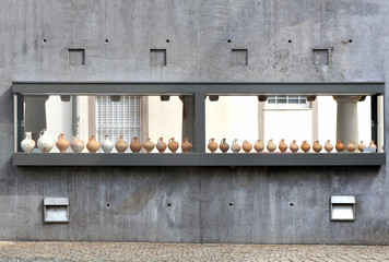 Concrete wall with an exposition of different clay jugs. Front view. Speyer, Germany