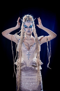 emotional actress woman in makeup and costume queen of elves or snow queen on blue-black background