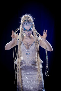 emotional actress woman in makeup and costume queen of elves or snow queen on blue-black background
