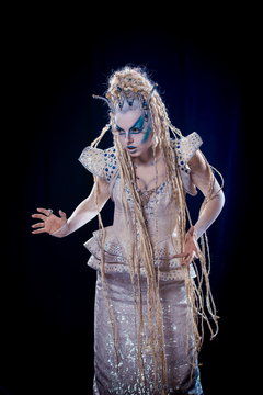emotional actress woman in makeup and costume queen of elves or snow queen on blue-black background